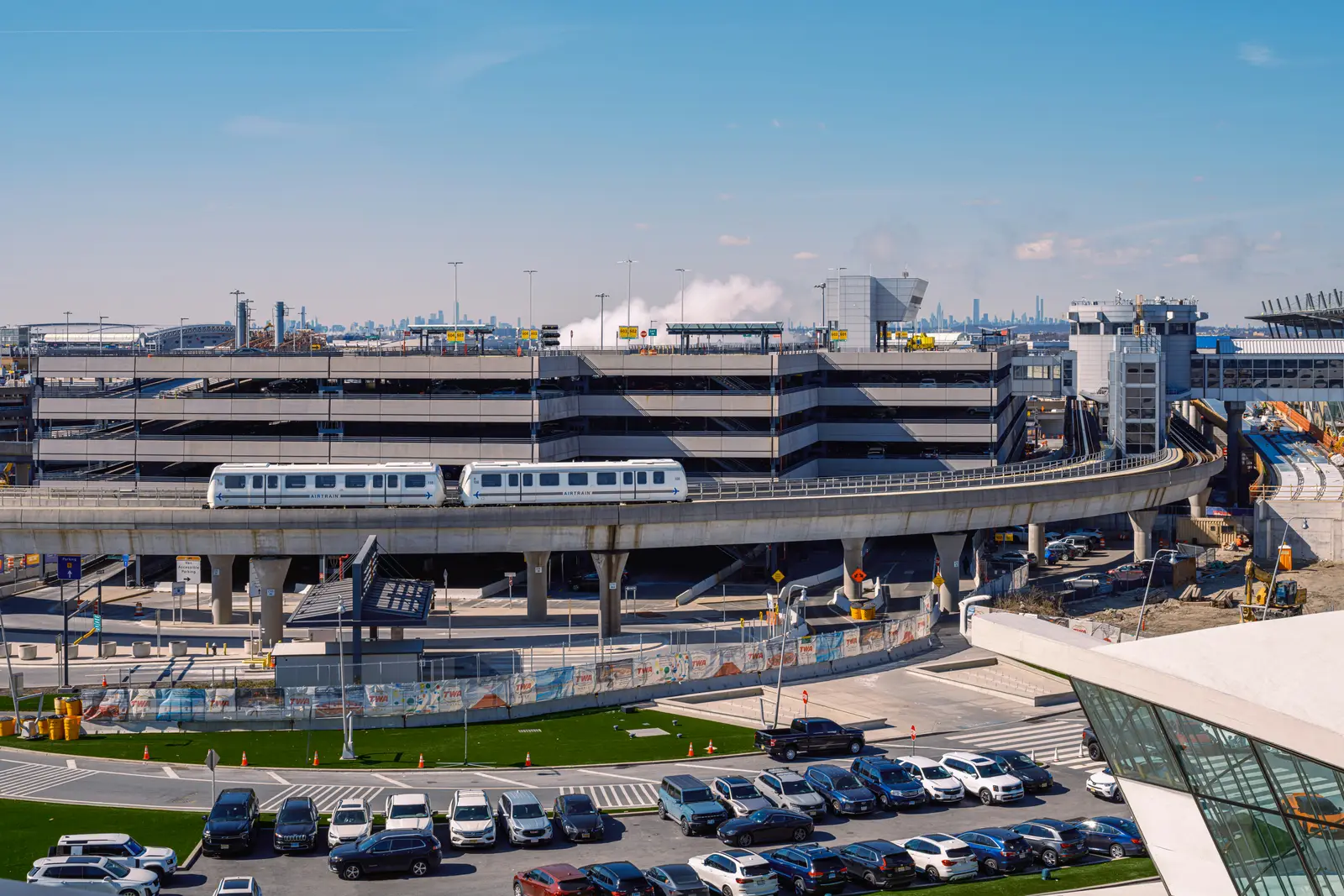 Mehrstöckiges Parkhaus am Flughafen mit Zubringerbahn und Stellplätzen davor